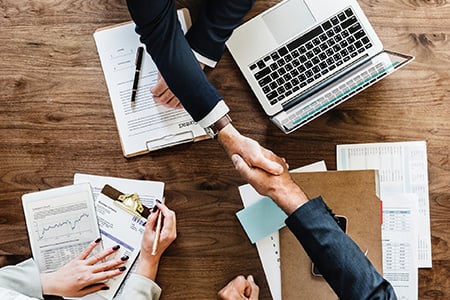 Two Professionals Shaking Hands Across a Workdesk